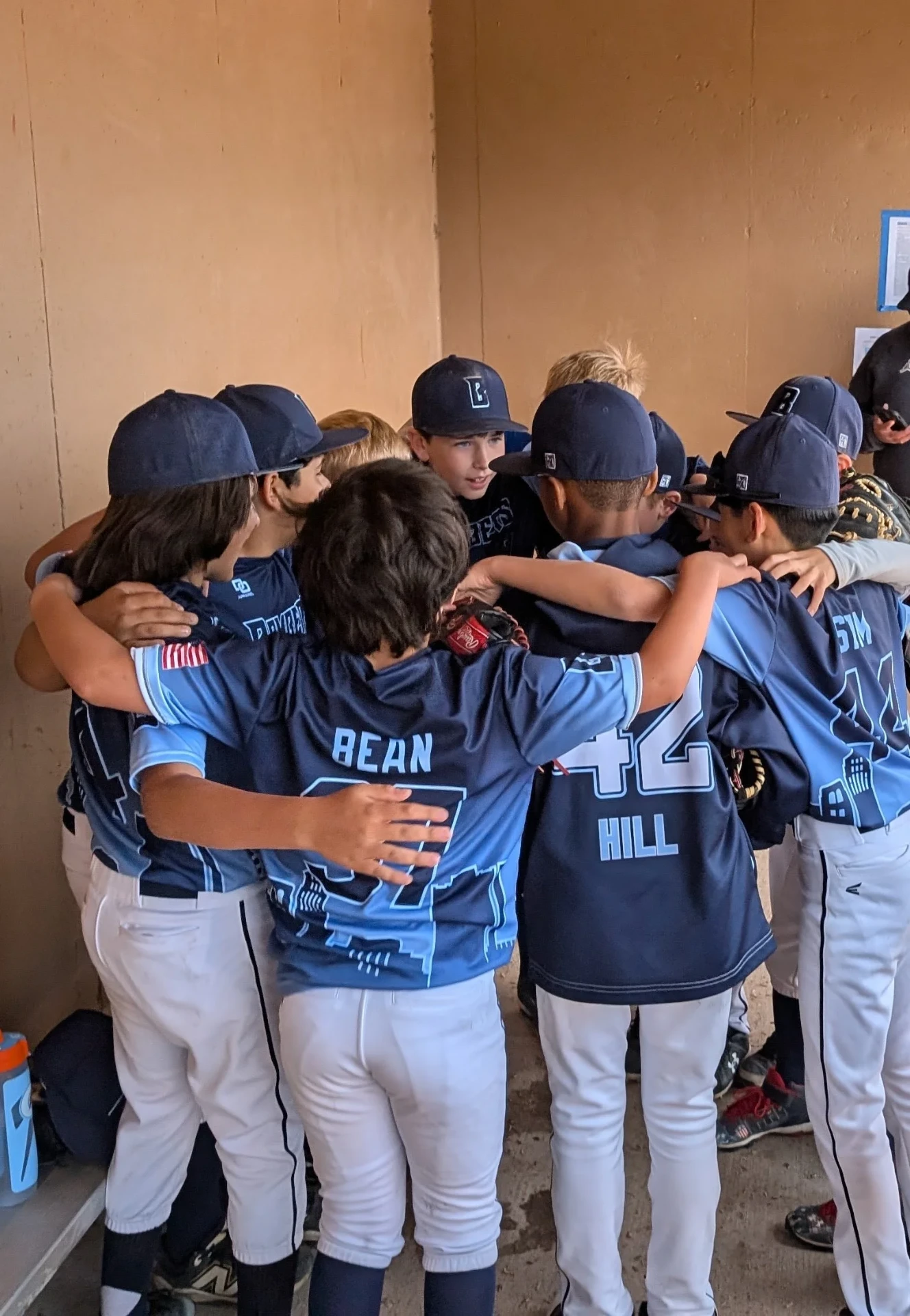 Bombers players in a tight dugout huddle, arms around each other